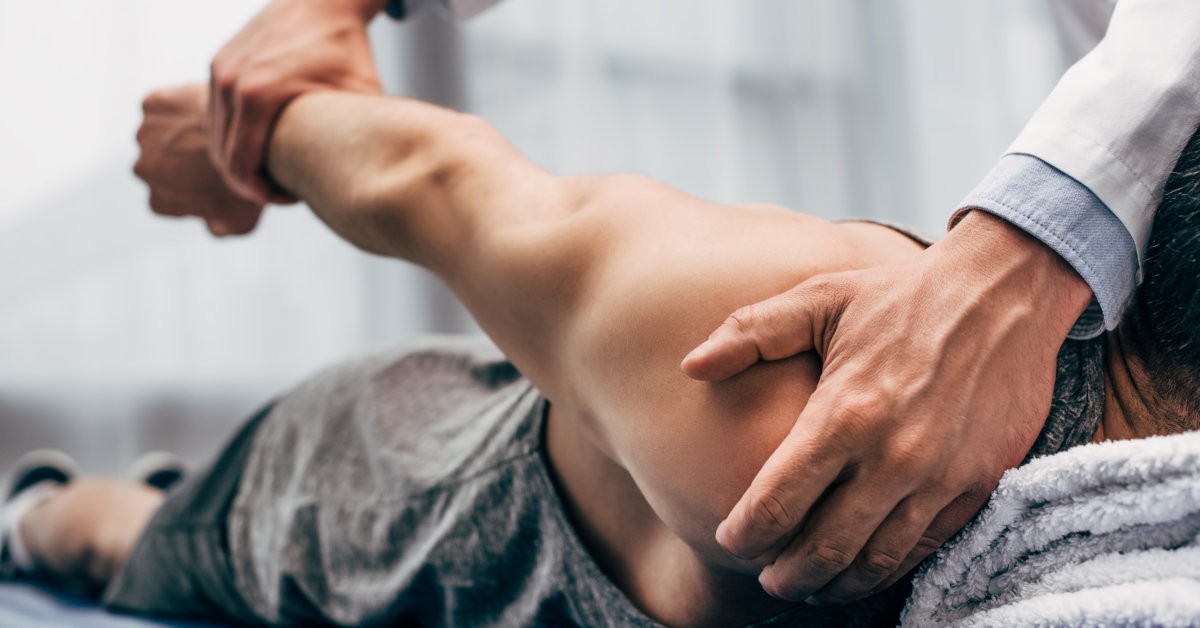 Doctor holding patient's shoulder and wrist